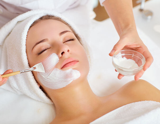 Hands applying moisturizing cream to a woman's face